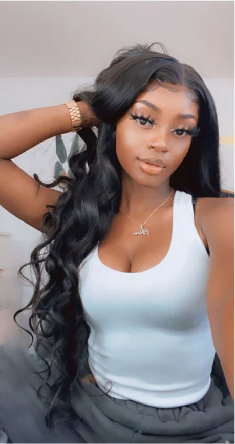 petty woman wearing 3 bundles of 30-inch virgin Brazilian bodywave shes wearing a white tank top and grey sweatpants