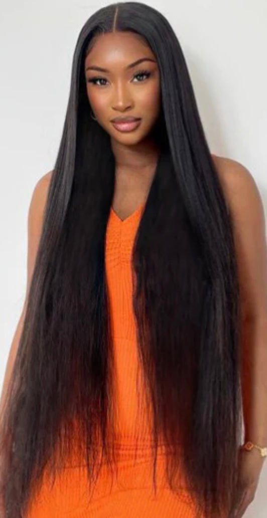 pretty woman wearing 3 bundles of bone straight virgin Brazilian hair in the lengths 26"28" and 30 inches she's wearing an orange dress standing in front of a white background